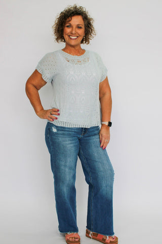 Woman wearing a light gray sweater and blue jeans on a white background