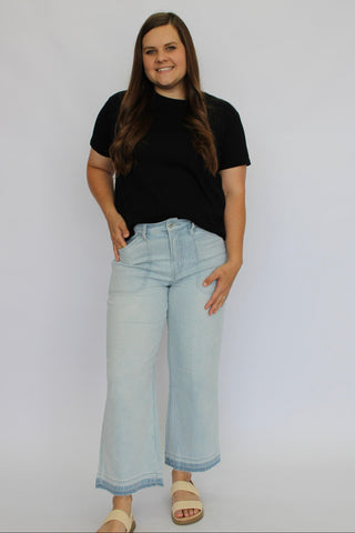 Woman wearing a black t-shirt and light blue jeans against a white background