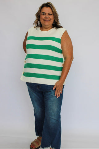 Woman wearing a green and white striped sleeveless top and blue jeans against a white background