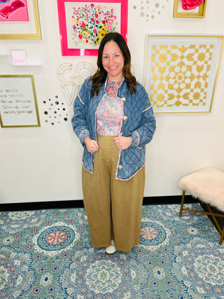 Woman standing with a denim jacket and khaki pants
