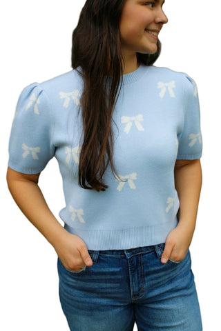 Woman wearing a light blue sweater with bow patterns on a black background