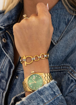 Gold watch and bracelet on a wrist with denim jacket
